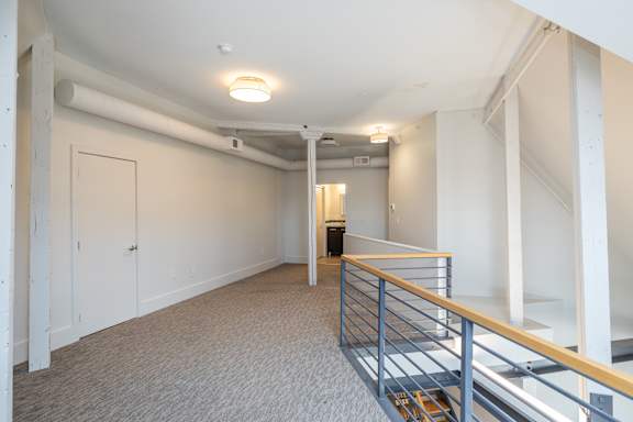 a renovated living room with stairs and a door to a hallway