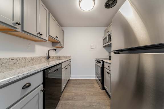 A kitchen with a stainless steel refrigerator and a marble countertop.