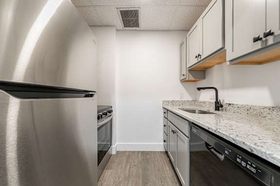 A kitchen with a stainless steel refrigerator and a granite countertop.