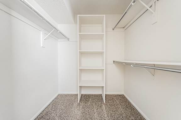 A white shelving unit in a room with a carpeted floor.at Hunt Club Apartments, Copley, OH