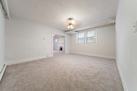 A spacious room with a carpeted floor and a window.