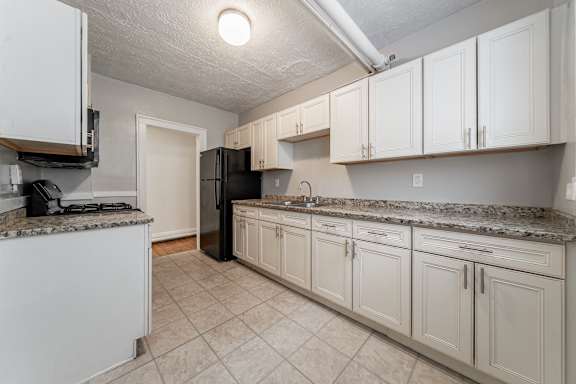 A kitchen with white cabinets and a granite countertop.