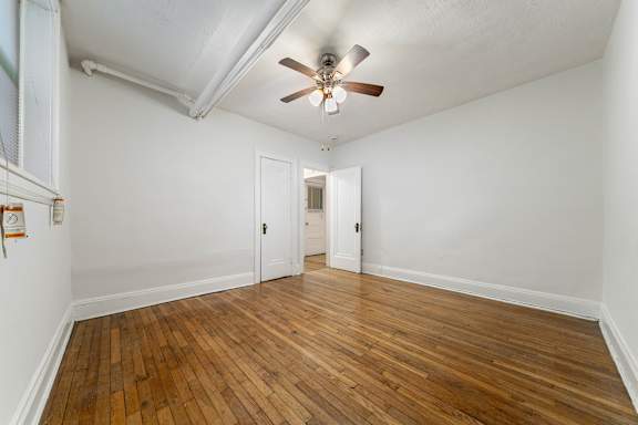 A room with a ceiling fan and wooden floors.