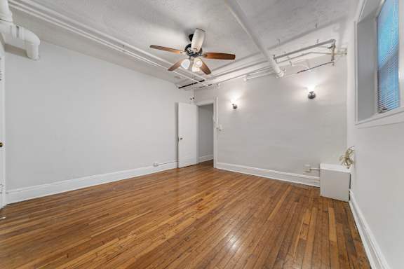 A room with wooden floors and a ceiling fan.