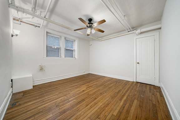 A room with a ceiling fan and wooden flooring.