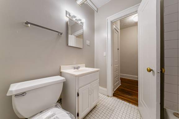 A white bathroom with a toilet, sink, and a mirror.