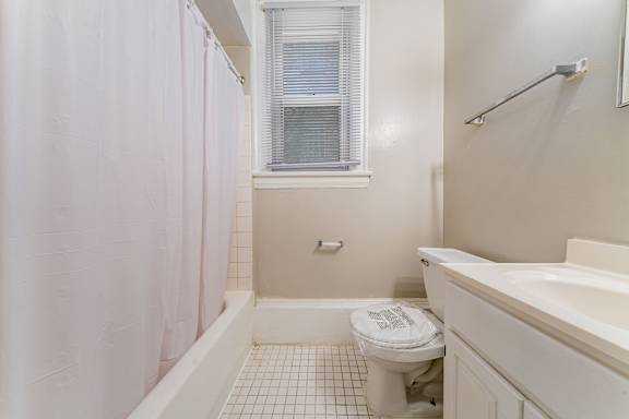 A white toilet sits in a bathroom next to a bathtub.