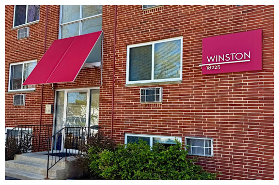 A red awning is over a glass door.