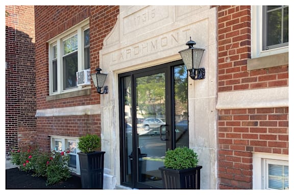 A red awning is on the front door of a brick building.