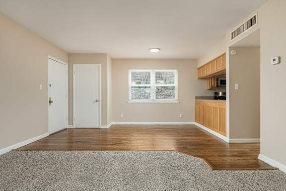 A room with a grey carpet and wooden flooring.