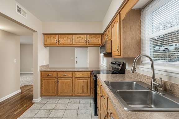 A kitchen with wooden cabinets and a stainless steel sink.