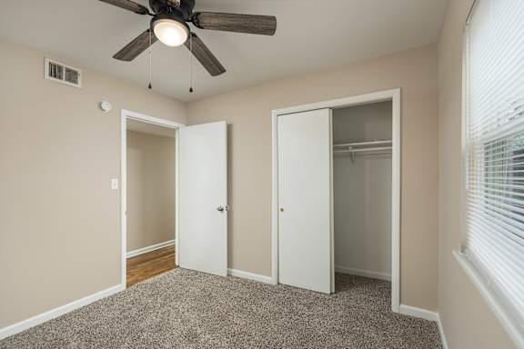 A room with a ceiling fan and three doors.