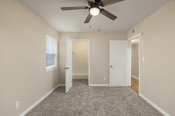 A room with a ceiling fan and carpeted floor.