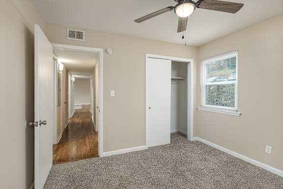 A room with a ceiling fan and a window with blinds.