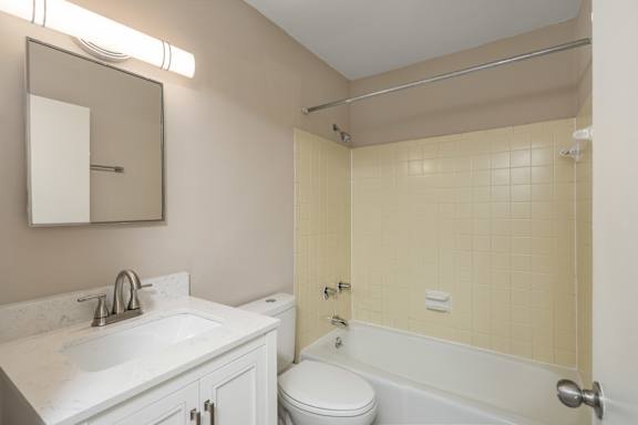 A bathroom with a white sink, toilet, and bathtub.