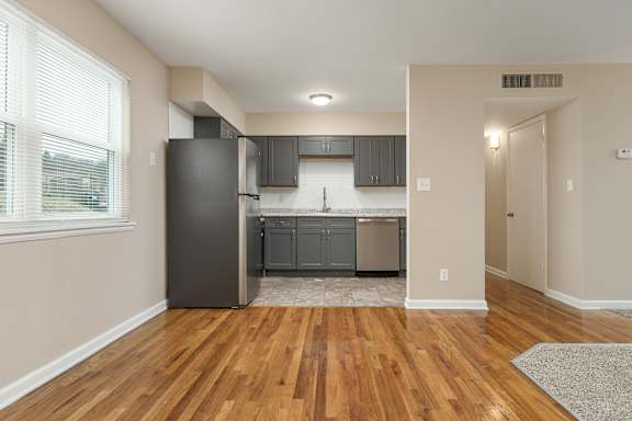 A kitchen with wooden floors and a black refrigerator.