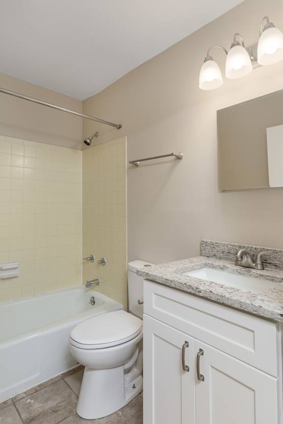 A white toilet sits in a bathroom next to a sink.