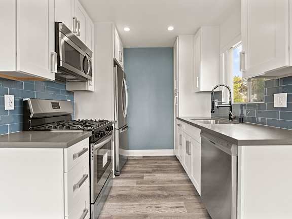 A modern kitchen with white cabinets and stainless steel appliances.