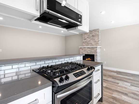 A modern kitchen with a black stove top oven and a microwave above it.