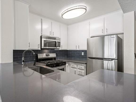 A kitchen with a stainless steel refrigerator and a black stove top.