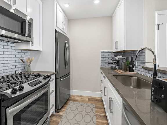 A modern kitchen with a stove, refrigerator, and microwave.