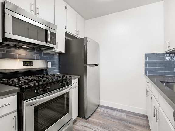 A kitchen with a stove, oven, microwave, and refrigerator.