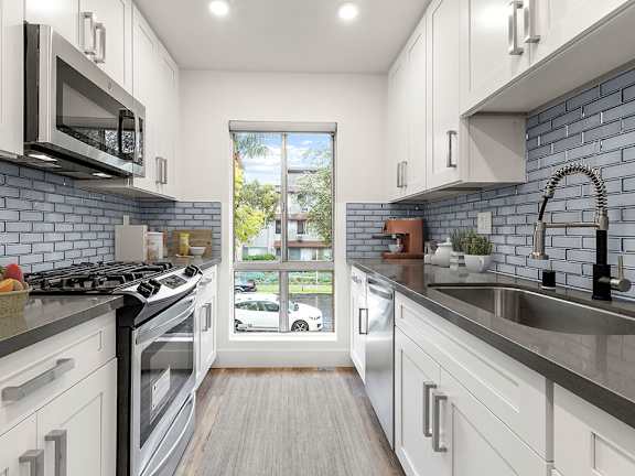 A modern kitchen with white cabinets and a black stove top.