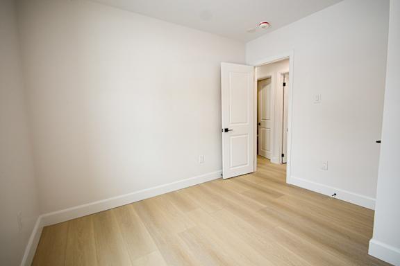 A room with a white door and wooden floor.