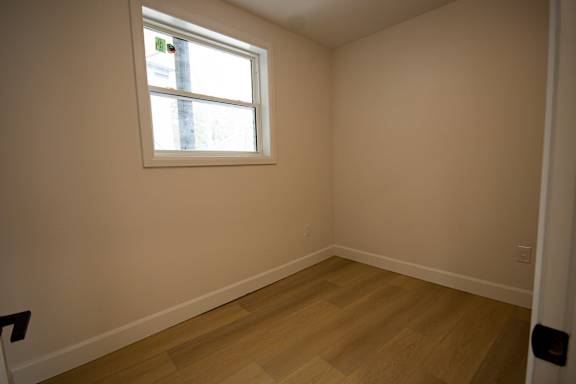 A room with a window and wooden flooring.