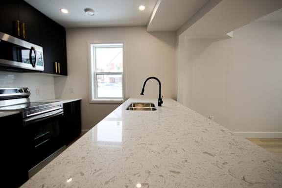 A kitchen with a white counter top and black cabinets.