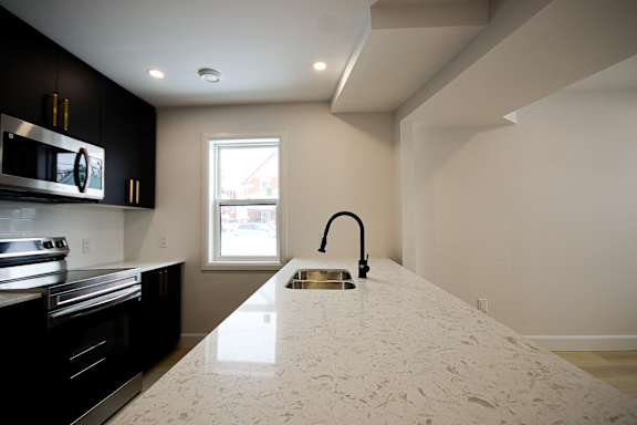 A modern kitchen with a white countertop and black cabinets.