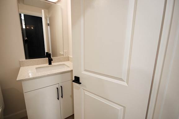 A white bathroom with a sink and mirror.
