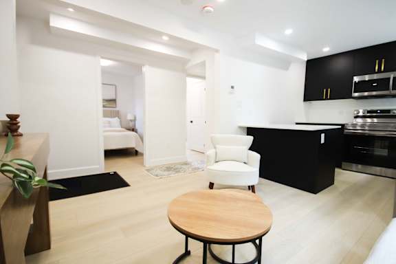 A modern kitchen with a black counter and a white chair.