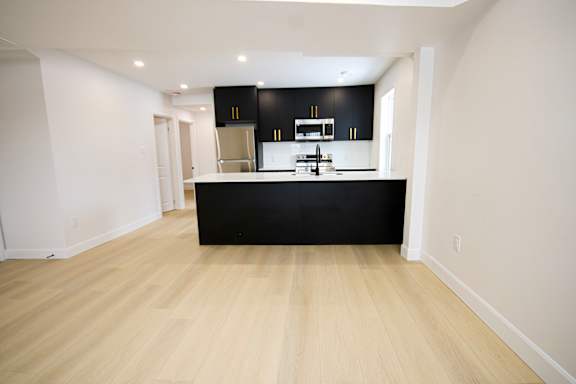 A kitchen with black cabinets and a wooden floor.