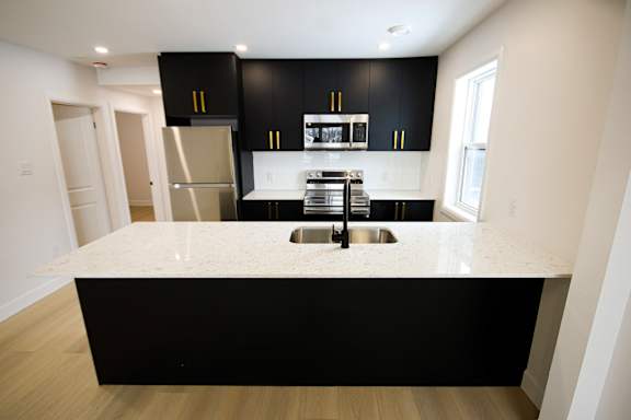 A kitchen with black cabinets and a white island.