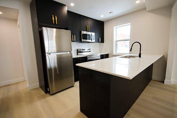 A modern kitchen with a stainless steel refrigerator and black cabinets.