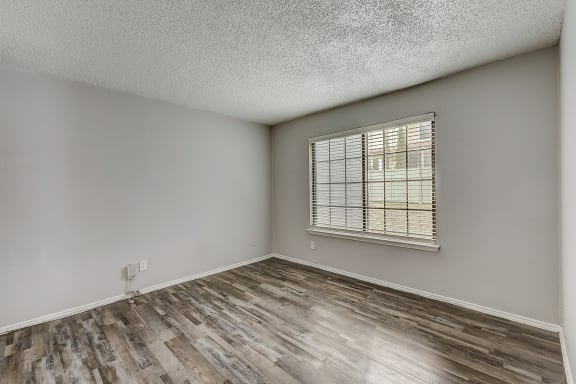 an empty bedroom with hardwood floors and a large window