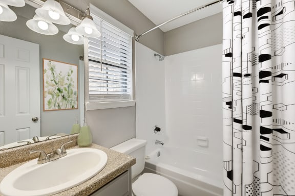 a bathroom with a white tub and toilet next to a sink with a mirror and a shower
