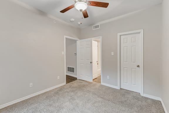 a bedroom with two doors and a ceiling fan