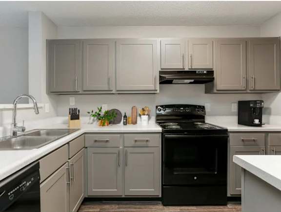 A kitchen with a black stove top oven and white countertops.