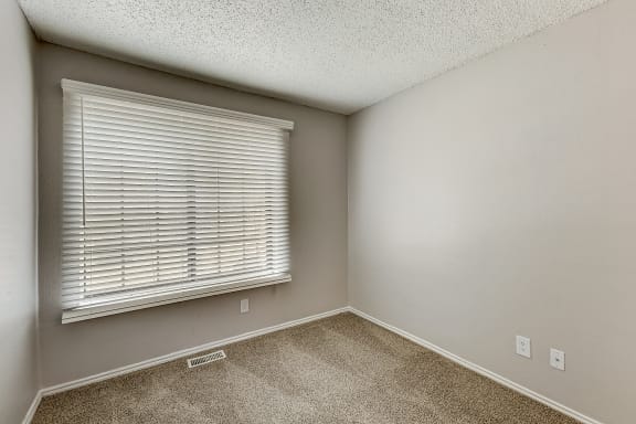 a bedroom with a large window and a carpeted floor