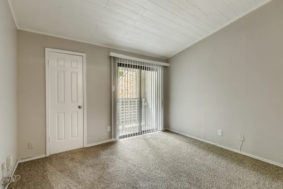 a bedroom with a sliding glass door and carpeted floor