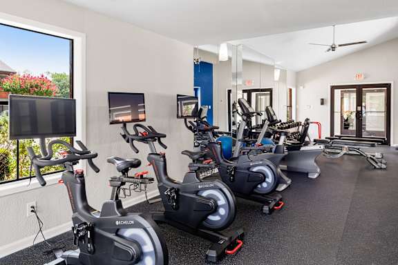 A gym with stationary bikes and a TV screen.