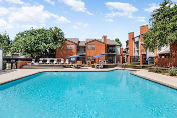 A large swimming pool in front of a building with a red brick exterior.