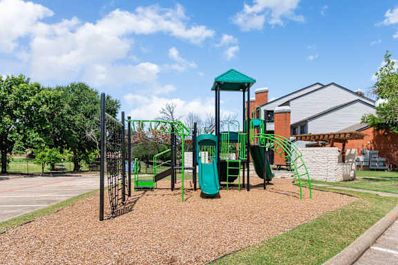 A playground with a green slide and a green roofed structure.