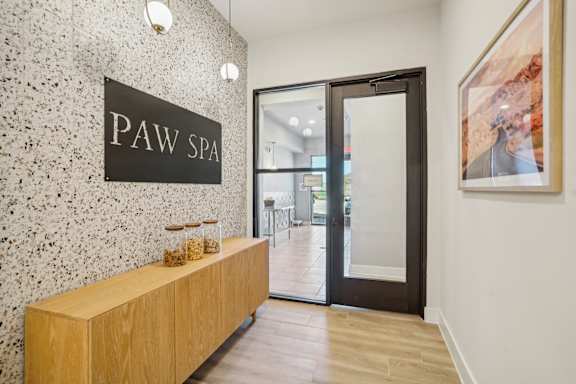 a lobby with a pay spa sign on the wall and a wooden reception desk