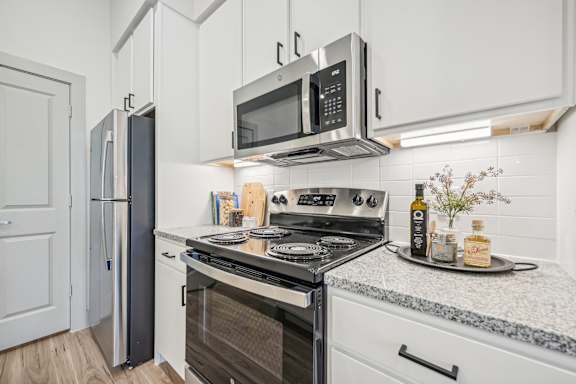 a kitchen with white cabinets and a stove and a microwave