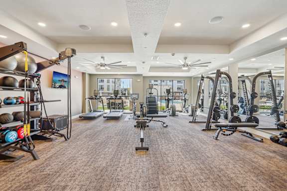 a gym with weights and cardio equipment in a building with windows