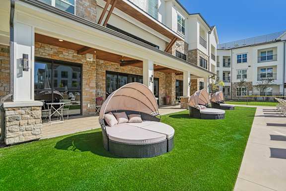 a patio with round chairs and a lawn in front of a building