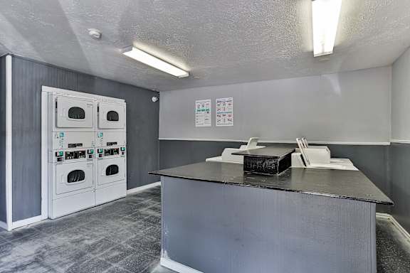 A room with a grey counter and a grey wall with a white oven.